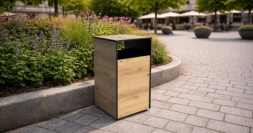 Corbeille urbaine en HPL placée près d’un massif de plantes dans un espace public